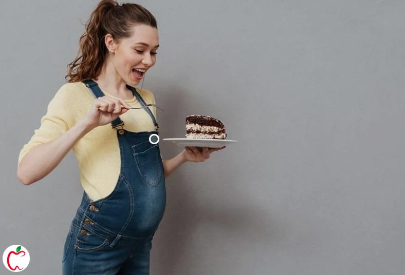 زنی باردار در حال خوردن شیرینی | مصرف شيرينی در دوران بارداری |سیوطب