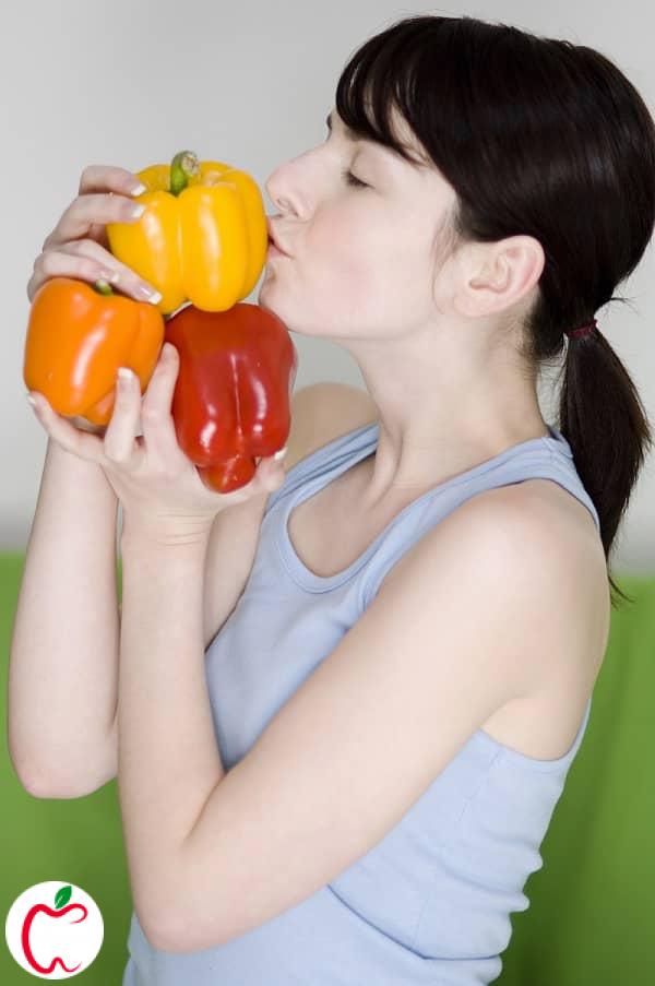 زن جوانی با چند فلفل قرمز و زرد در دستش | تغذیه دوران قاعدگی | سیوطب