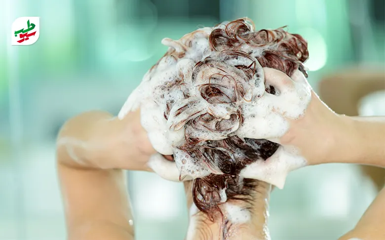 شخصی در حال شستن موهایش با شامپو برای درمان خانگی چربی سر|سیوطب