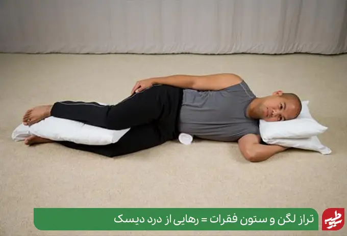 فردی به پهلو خوابیده که یک بالش بین زانوهای خود قرار داده روش صحیح نحوه استراحت برای درمان دیسک کمر|سیوطب
